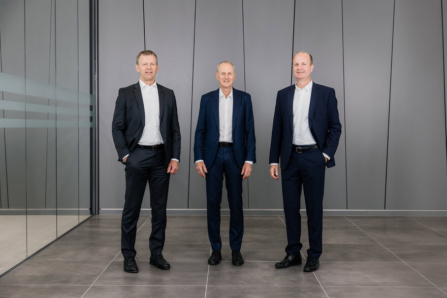 Die Geschäftsführung von GROB posiert selbstbewusst in einem stilvollen, minimalistischen Büro mit großen Fenstern.