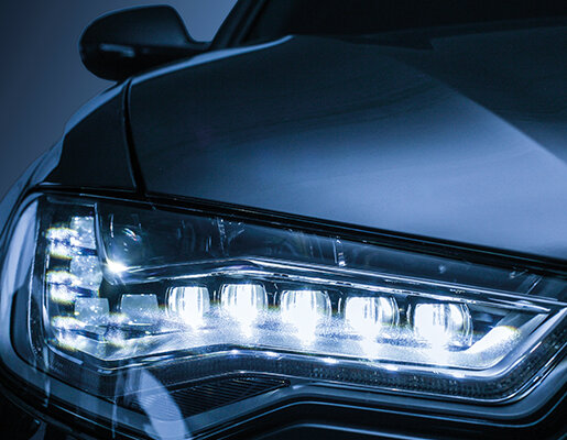 Der Scheinwerfer eines modernen Fahrzeugs strahlt helles Licht aus und hebt die elegante Linienführung des Autos hervor.
