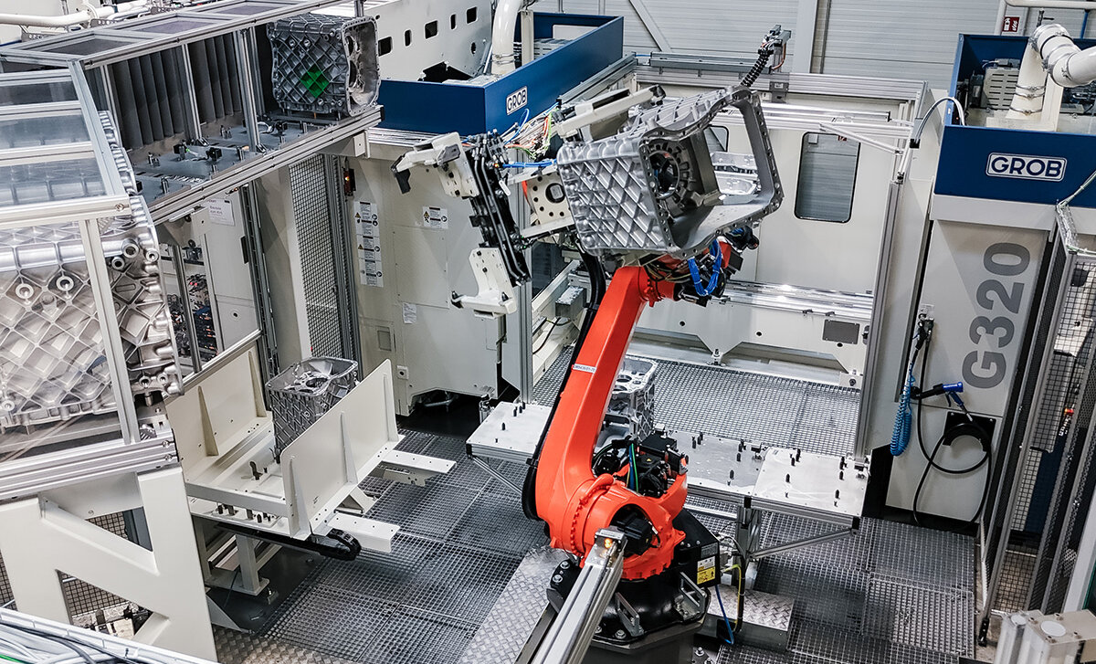 Ein Roboterarm in der Mitte der Fertigungslinie bewegt ein Werkstück.
