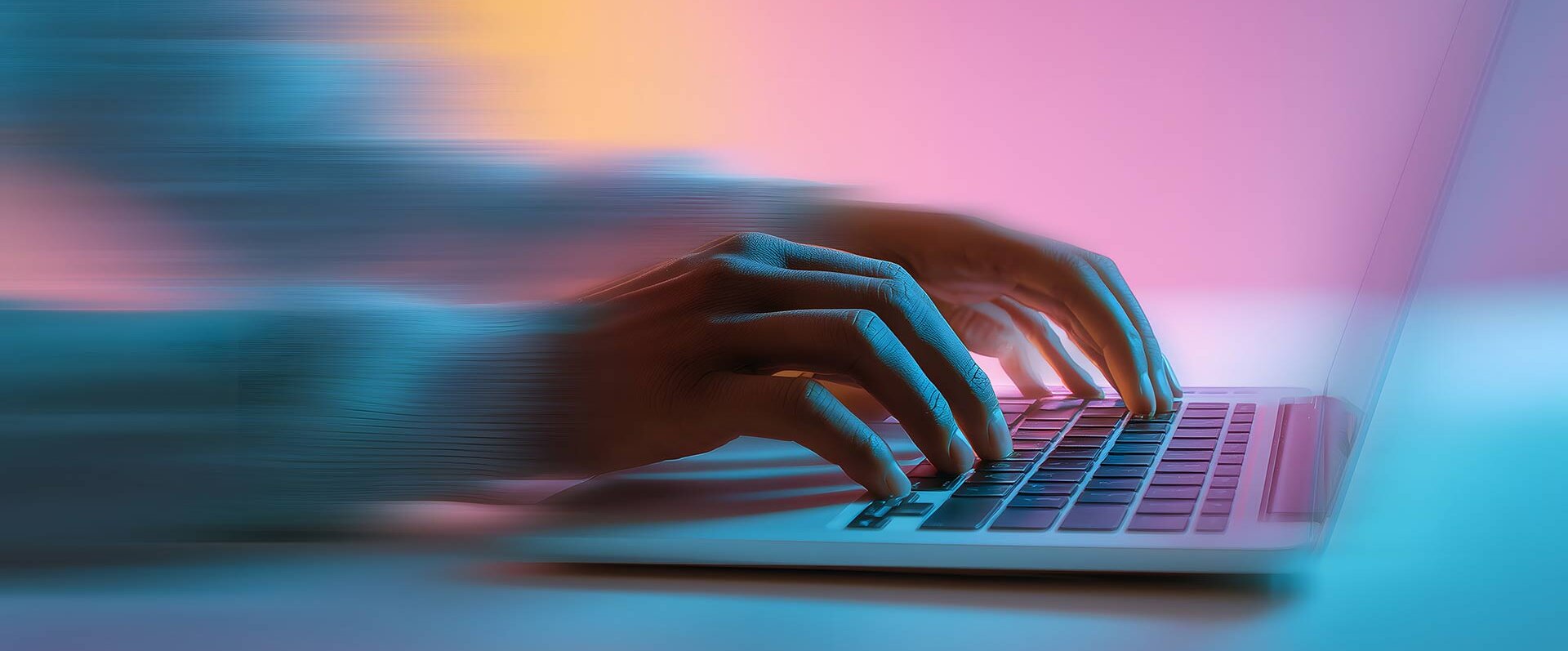 Eine Hand tippt schnell auf einer Laptop-Tastatur, umgeben von einem sanften, bunten Lichtspiel.