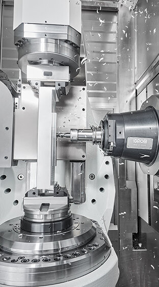 Eine hochmoderne GROB-Maschine bearbeitet präzise Metallteile, während Späne durch die Luft fliegen.