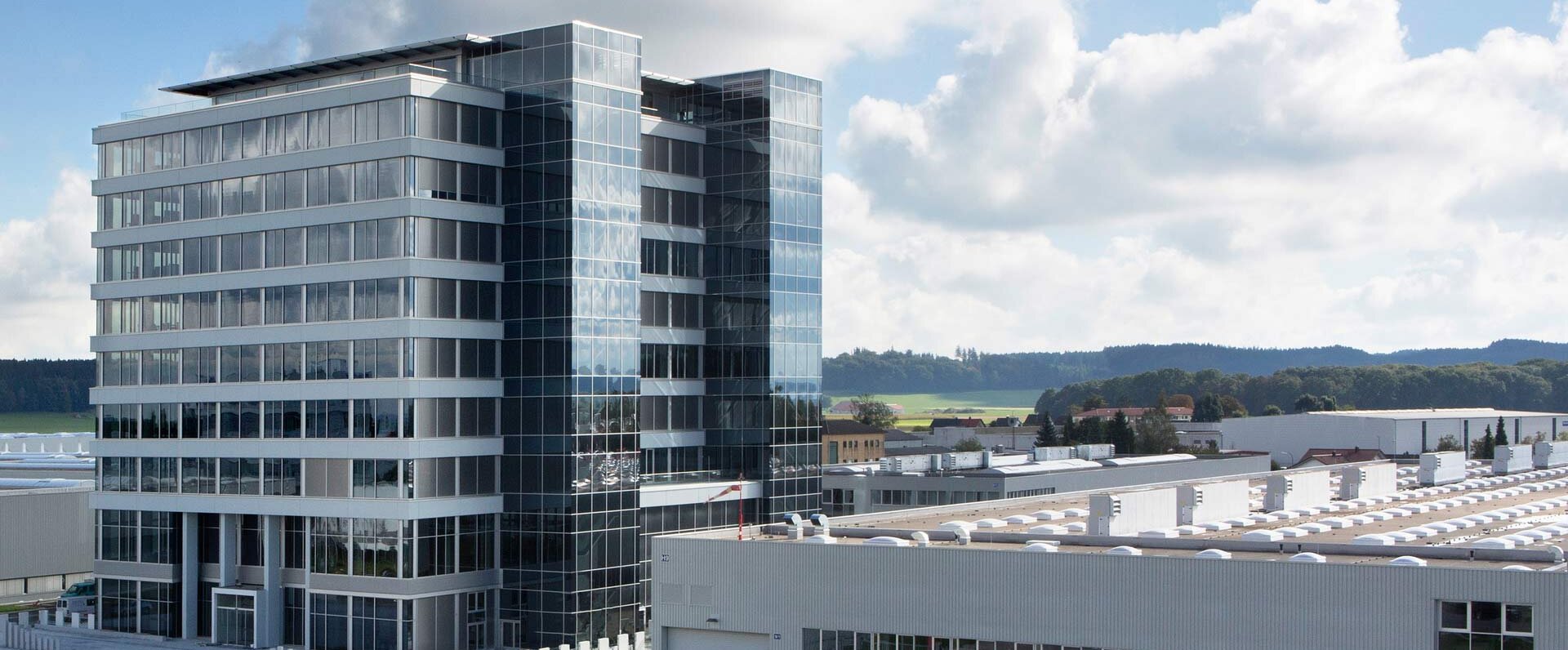Das moderne Bürogebäude von GROB in Mindelheim mit großen Glasfenstern und einem Hubschrauberlandeplatz im Vordergrund.