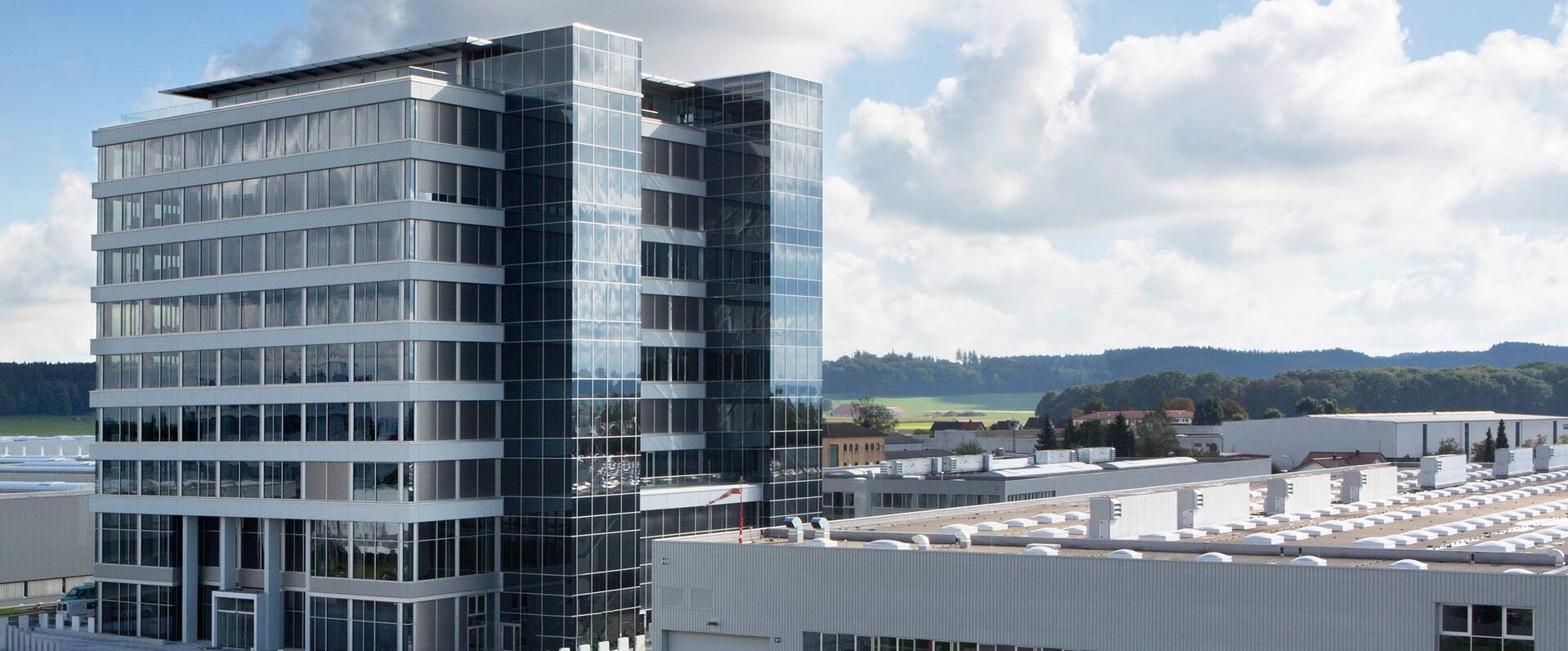 Das moderne Bürogebäude von GROB in Mindelheim mit großen Glasfenstern und einem Hubschrauberlandeplatz im Vordergrund.