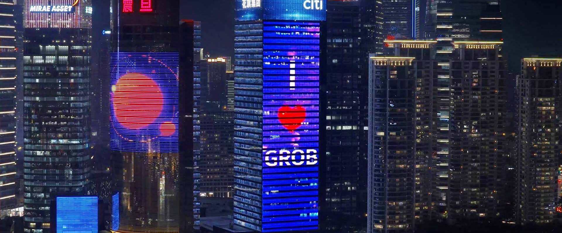 Ein beleuchtetes Hochhaus in Dalian zeigt eine große digitale Anzeige mit der Botschaft 'I ❤️ GROB'.