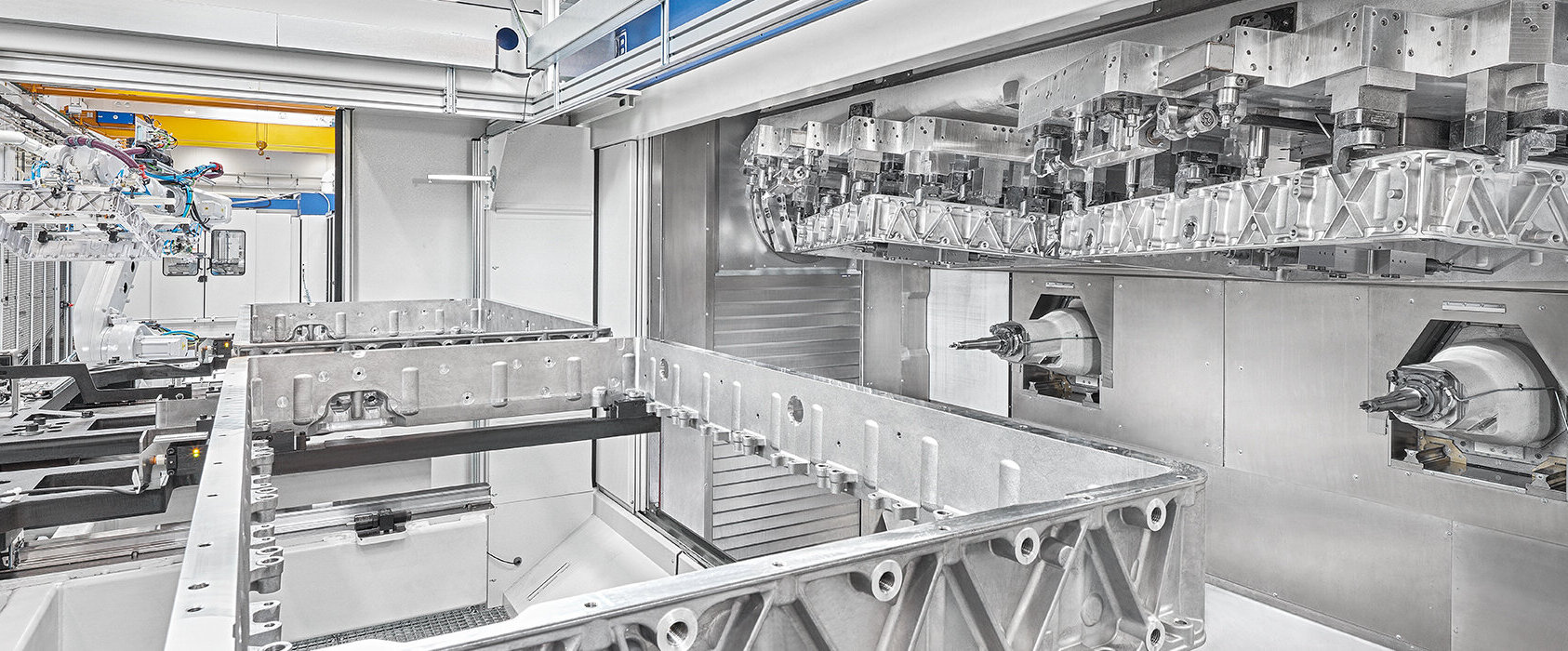 Eine hochmoderne Fertigungsanlage zeigt präzise Zerspanungstechnik mit einem großen, bearbeiteten Aluminiumteil im Vordergrund.