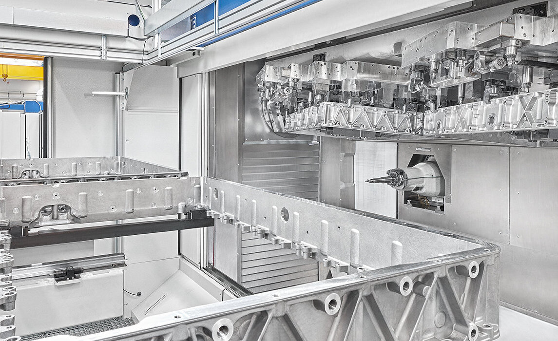 Eine hochmoderne Fertigungsanlage zeigt präzise Zerspanungstechnik mit einem großen, bearbeiteten Aluminiumteil im Vordergrund.