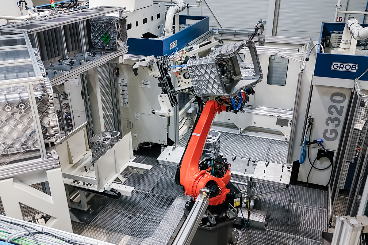 Ein Roboterarm in der Mitte der Fertigungslinie bewegt ein Werkstück.